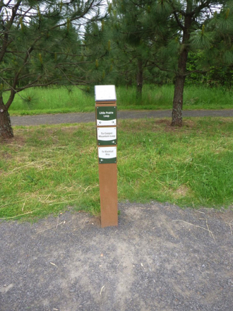 The main compacted gravel trail has directional signage with a park map on top The main compacted gravel trail has directional signage with a park map on top